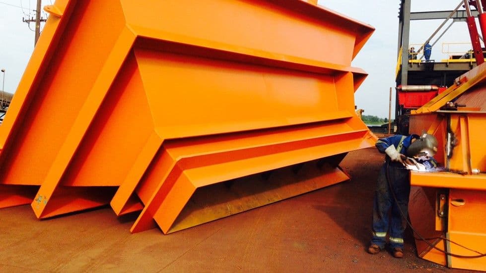 welder in construction welding an orange hopper